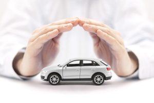 Car insurance. Small silver car covered by hands.